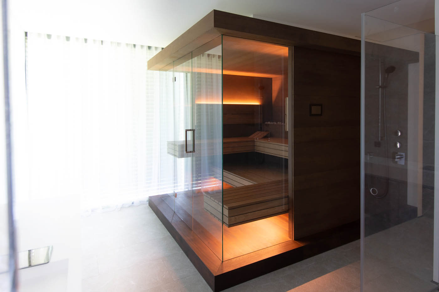 Sauna NIMBUS 3 Sauna mit Glasfront im Badezimmer: Dreiseitig verglaste Designsauna als Variation der NIMBUS Sauna mit LED Beleuchtung im Bad.