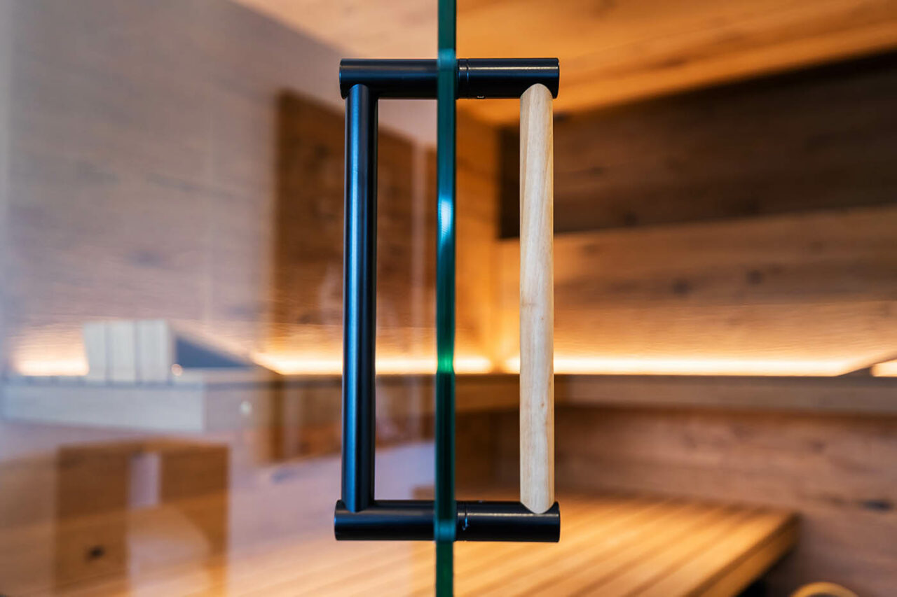 Garagen-Metamorphose: Ecksauna mit Glasfront. 189 schwarze Beschläge Ecksauna in Eiche und Thermo-Espe mit zweiseitiger Verglasung, schwebenden Bänken, Hinterwandofen und verdeckt eingebautem Infrarot Strahler