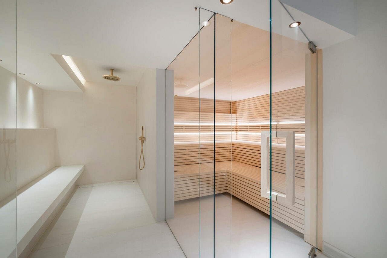 Sauna design lumineux avec poêle derrière banquettes 8 Design Sauna im Bauhausstil mit Hinterwandofen. Saunaholz: helle Espe in Stäbchenoptik. Große Glasfront, LED Beleuchtung, Hinterwandofen.