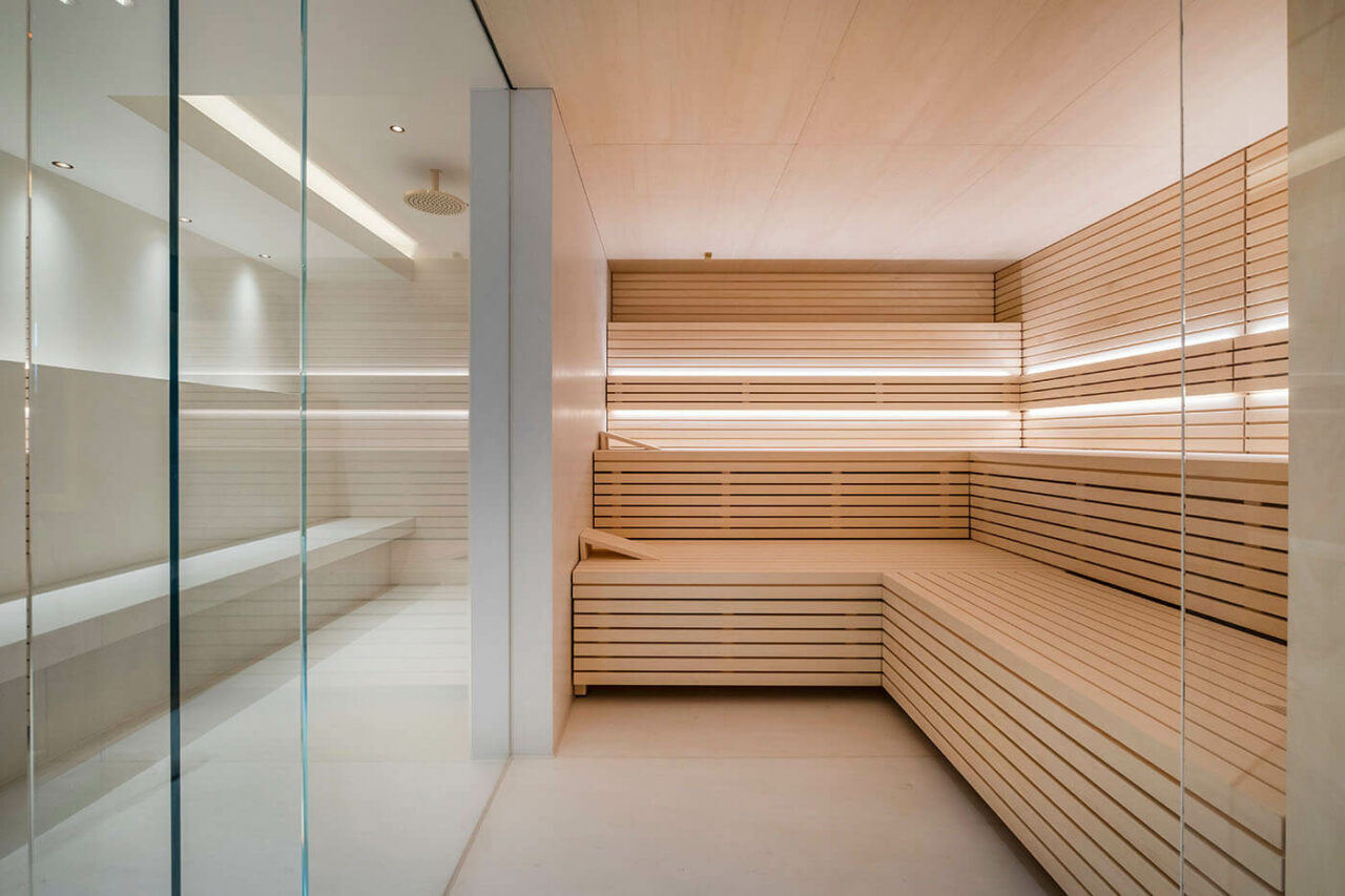 Sauna design lumineux avec poêle derrière banquettes 5 Design Sauna im Bauhausstil mit Hinterwandofen. Saunaholz: helle Espe in Stäbchenoptik. Große Glasfront, LED Beleuchtung, Hinterwandofen.