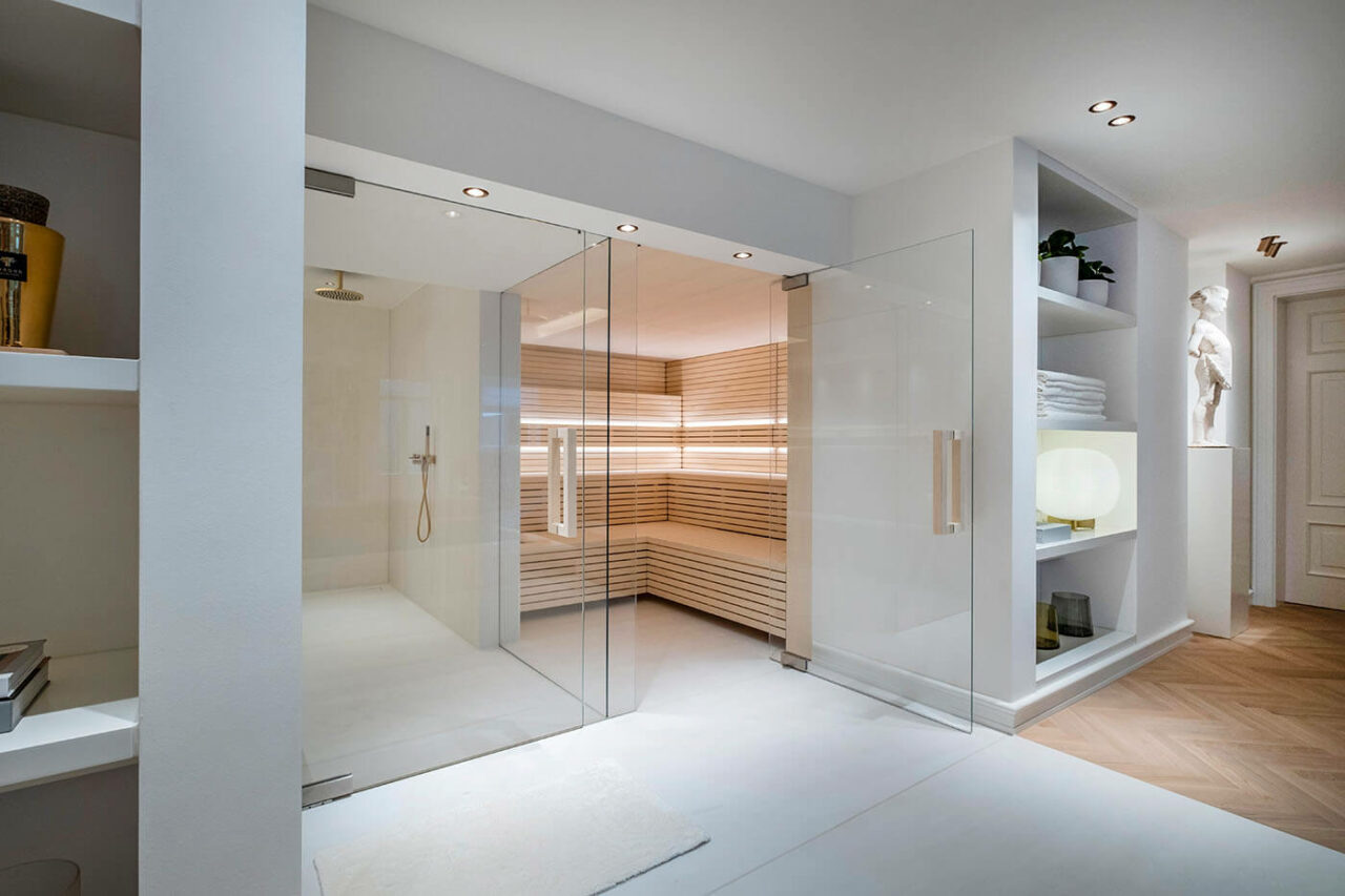 Sauna design lumineux avec poêle derrière banquettes 2 Design Sauna im Bauhausstil mit Hinterwandofen. Saunaholz: helle Espe in Stäbchenoptik. Große Glasfront, LED Beleuchtung, Hinterwandofen.