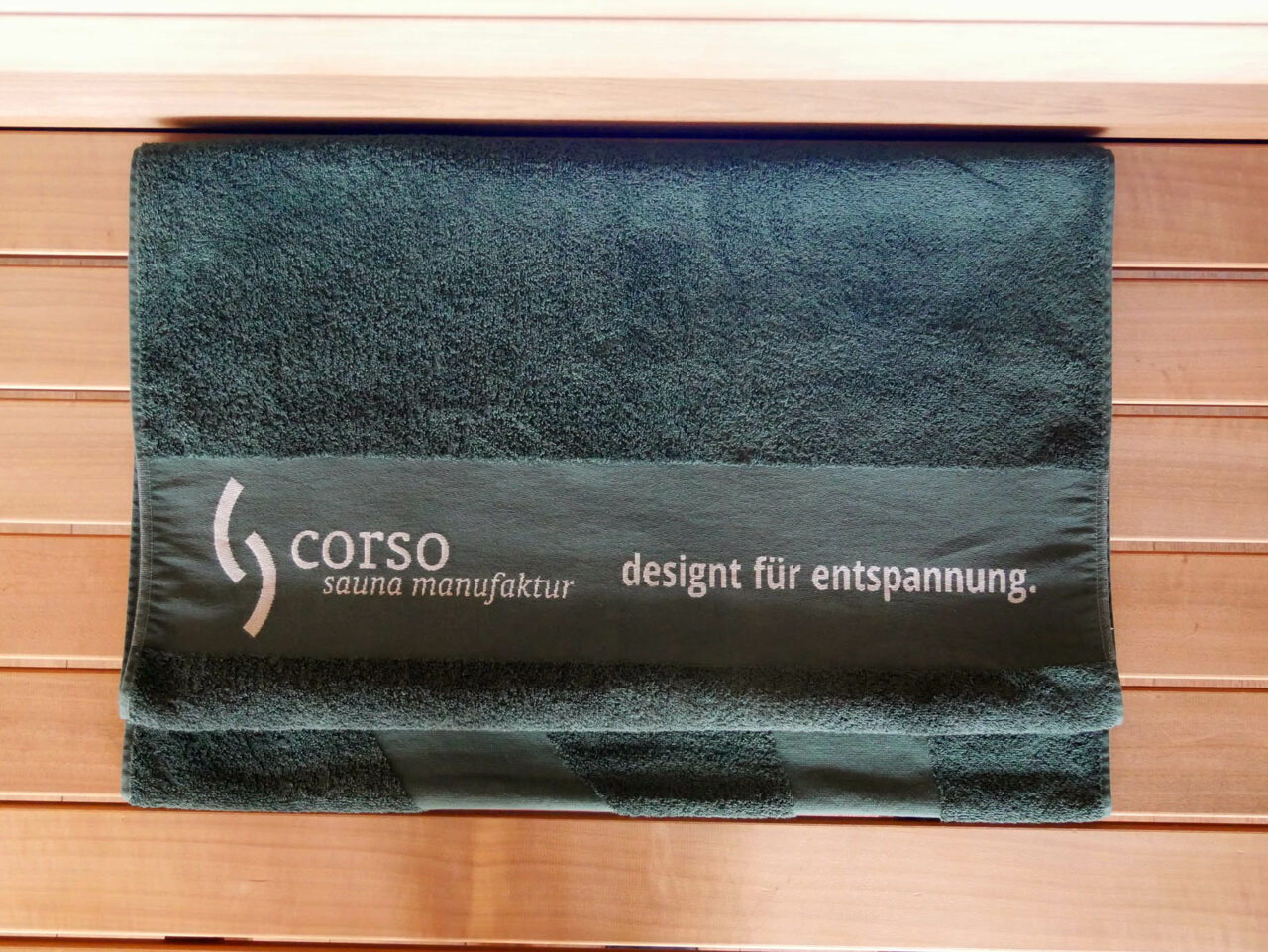 Sauna Zubehör 3 Sauna Zubehör: dunkelgrünes Saunahandtuch / Saunatuch XL mit corso Logo. Beste Qualität in Bio-Baumwolle. Extra groß mit 70 x 200 cm. Erhältlich im corso e-Shop für Saunazubehör.