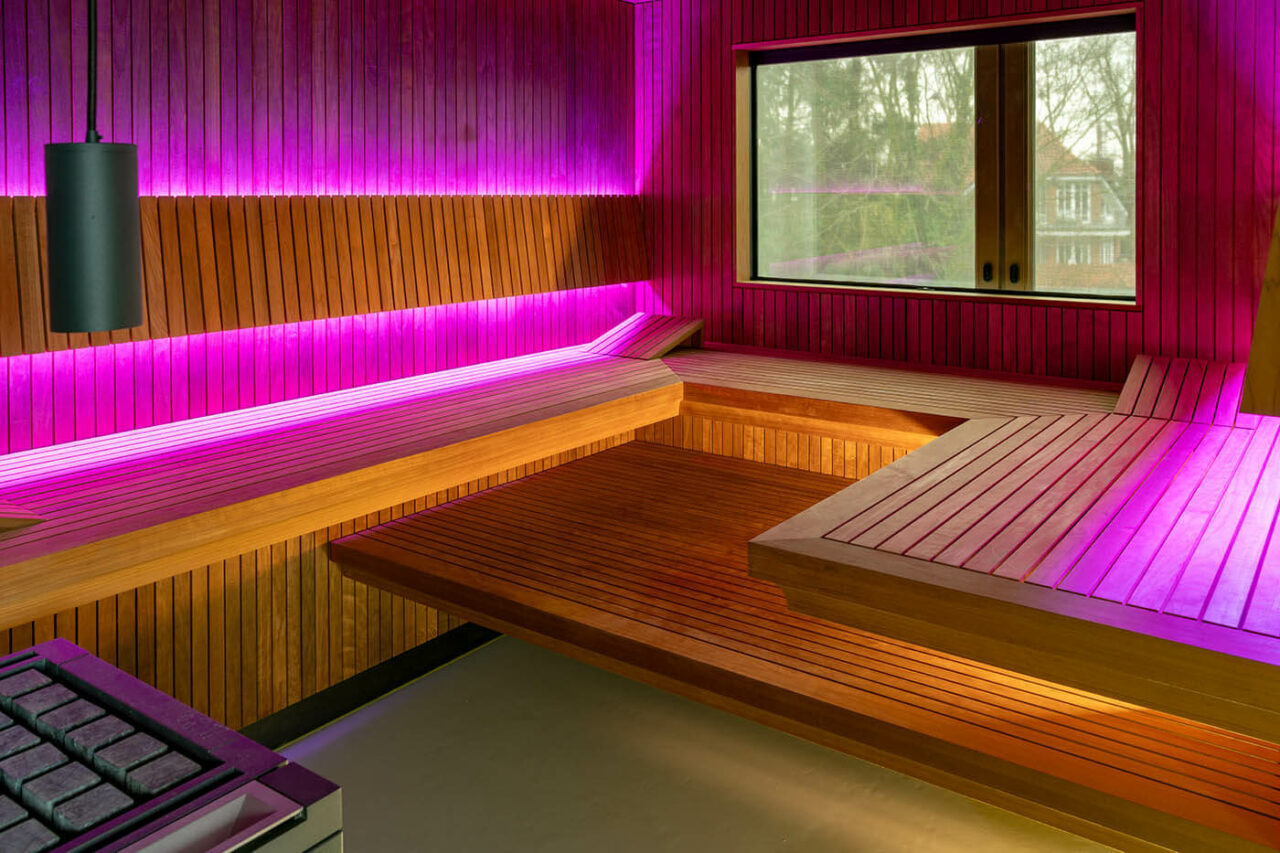 Sauna avec coin en verre à l’aspect baguettes 3 Design Sauna nach Maß mit Glasecke in Thermo-Espe Stäbchenoptik mit indirekter LED Rückenlehnenbeleuchtung und Außenfenster. Biosauna. Saunabau Münster.