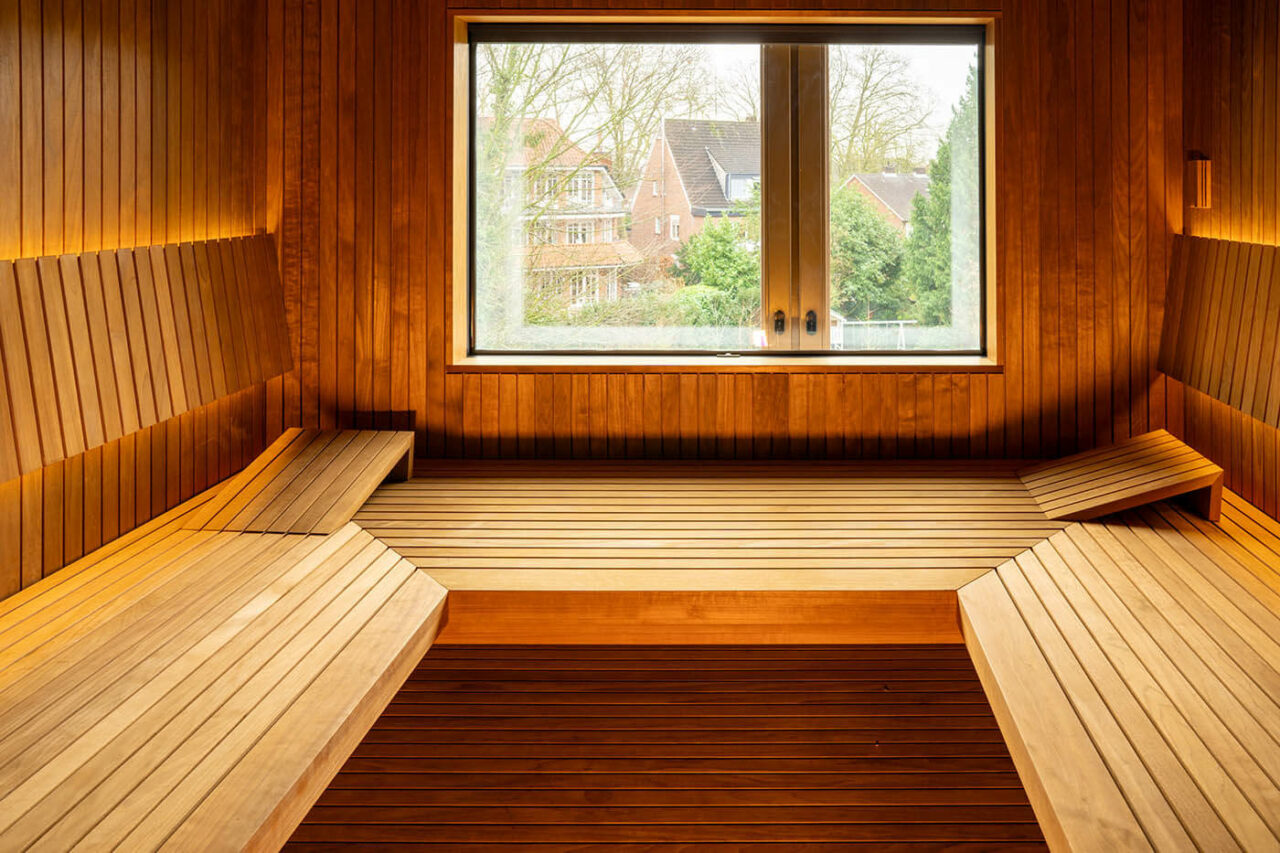 Sauna avec coin en verre à l’aspect baguettes 5 Design Sauna nach Maß mit Glasecke in Thermo-Espe Stäbchenoptik mit indirekter LED Rückenlehnenbeleuchtung und Außenfenster. Biosauna. Saunabau Münster.