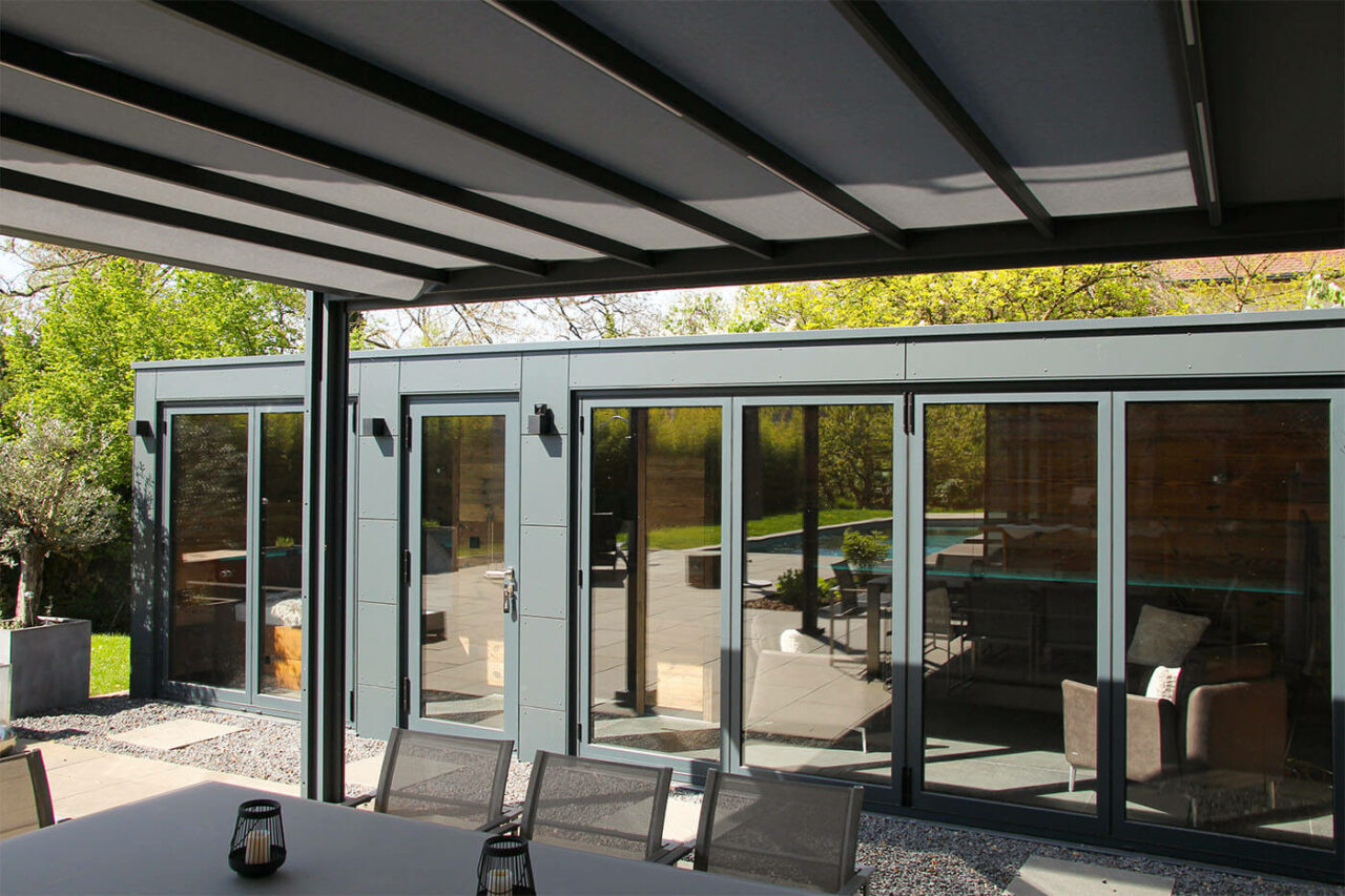 Pool house sur mesure avec façade vitrée 210 Poolhaus nach Maß mit zu öffnender Glasfront, Daybed, Kaffeeküche und Lounge. Außenverkleidung in wetterfesten Trespa Schichtstoffplatten.